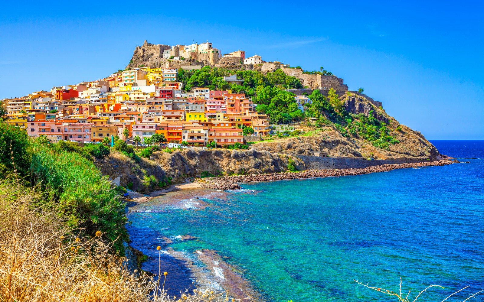 Castelsardo: 900 Anni di Storia, Arte e Tradizione Vicoli caratteristici di un borgo sardo con case in pietra e balconi Scorcio panoramico di Castelsardo con case colorate arroccate sul promontorio e il mare cristallino sullo sfondoioriti