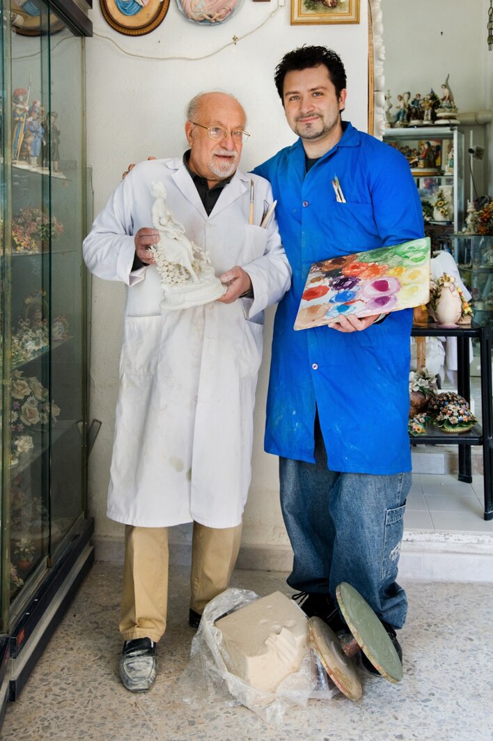 Giovanni e Giuseppe Carusio nel loro laboratorio artigianale: un passaggio di testimone nell'arte della ceramica e della porcellana da padre in figlio.