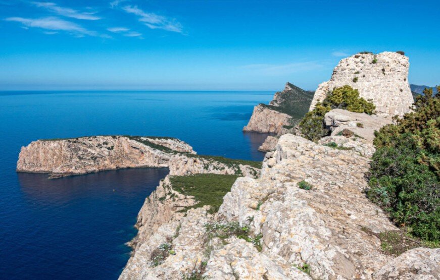 Trekking Selvaggio tra le Torri Saracene: 3 Percorsi per Esperti nel Nord-Ovest della Sardegna Torre della Pegna a picco sul mare: vista spettacolare della falesia calcarea durante il percorso di trekking a Capo Caccia, Sardegna.