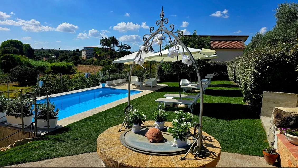 Piscina illuminata con luci blu e ombrelloni per eventi serali a Villa Malvasio Sassari
