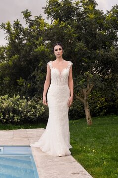 Modella che sfila con grazia indossando un abito da sposa sul bordo della piscina esterna circondata dal giardino.