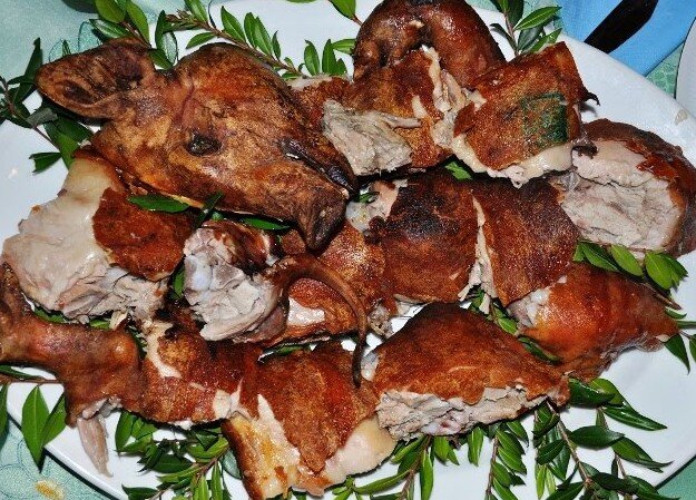 Porcetto arrosto servito su vassoio con mirto e pane carasau.