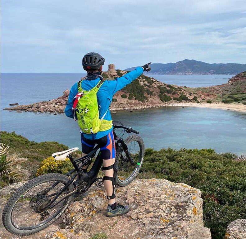Un ciclista in mountain bike si ferma lungo la strada costiera dell'Asinara per ammirare il paesaggio selvaggio e il mare cristallino
