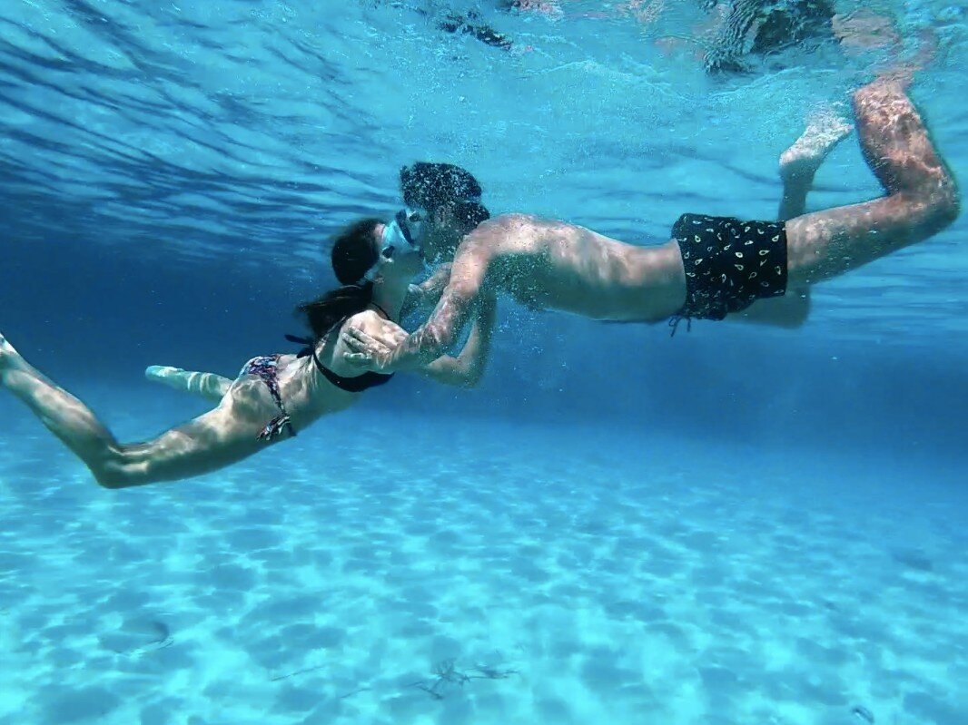 Una coppia si bacia teneramente immersa nelle acque trasparenti e color azzurro turchese del Golfo dell'Asinara durante un'escursione.
