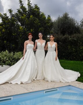 Tre bellissime modelle indossano abiti da sposa di alta moda nel rigoglioso giardino di Villa Malvasio vicino alla piscina.