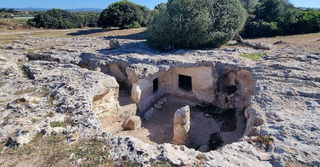 necropoli-su-crocifissu-mannu-porto-torres-sassari-villa-malvasio.jpeg Fotografia della necropoli preistorica di Su Crucifissu Mannu a Porto Torres, con gli ingressi delle domus de janas scavate nel banco di roccia calcarea orizzontale.