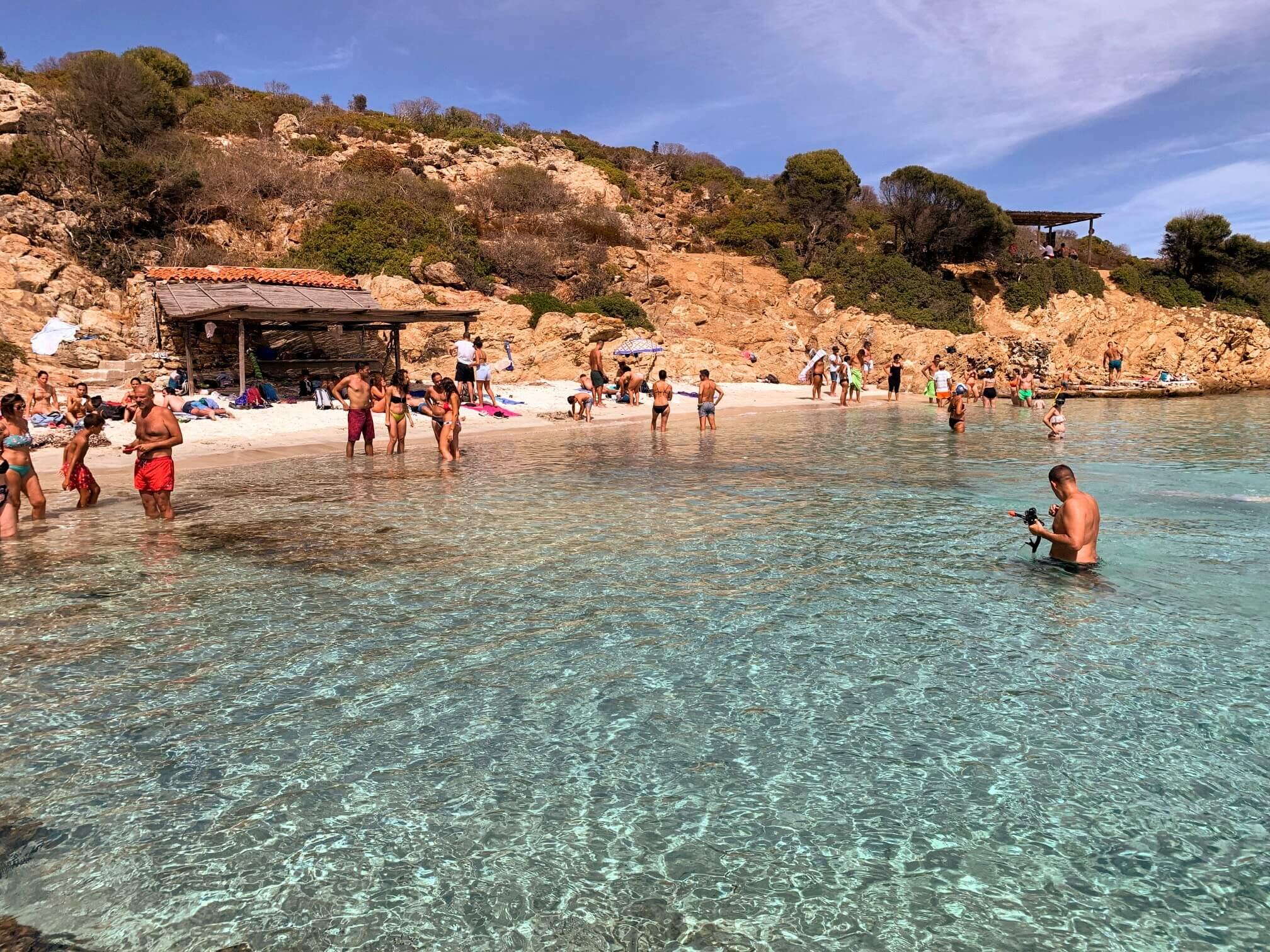 Turisti che fanno il bagno in una caletta dell'Asinara con acqua trasparente e cristallina