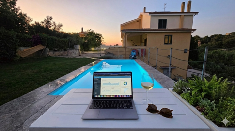 Postazione smart working a bordo piscina con computer e calice di vino a Villa Malvasio Sassari. Postazione smart working a bordo piscina con computer e calice di vino a Villa Malvasio Sassari.