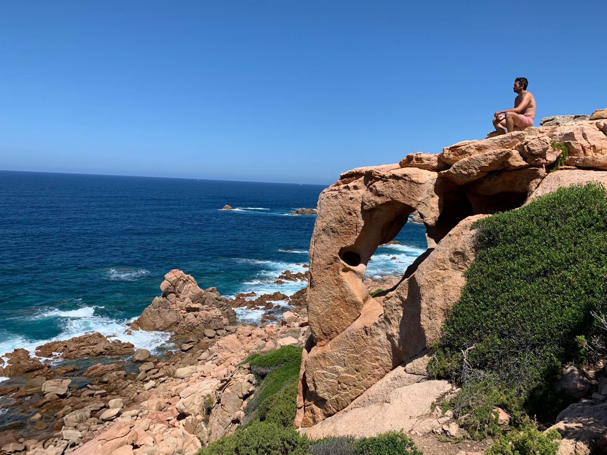 rocce-rosse-trachite-mare-sardegna.jpeg Spuntone di roccia rossa trachite a picco sul mare agitato Sardegna.