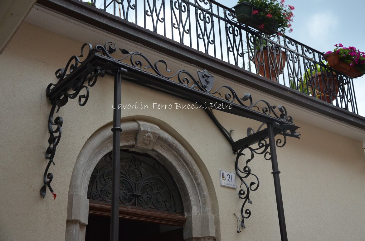 Copertura in vetro, greca superiore in ferro battuto artigianale con scudo con iniziale.