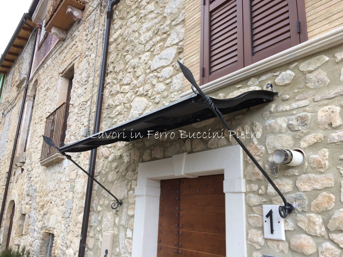 Andamento ad onda, copertura in lamiera. Dettagli di sostegno in ferro battuto artigianale.