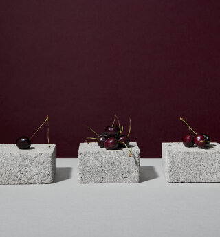 Still life con ciliegie ed elementi grigi su fondo bordeaux