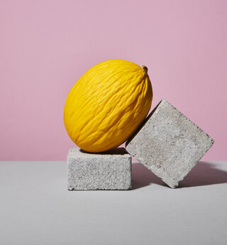 Still life di un melone giallo adagiato su elementi grigi