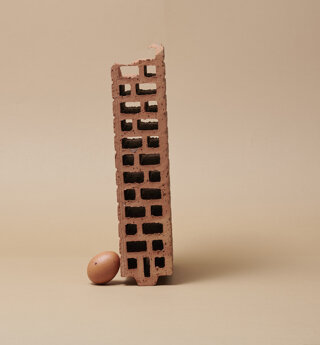 Still life di un uovo ed un mattone in bilico