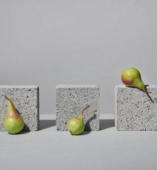 Still life con pere verdi ed elementi grigi su fondo grigio