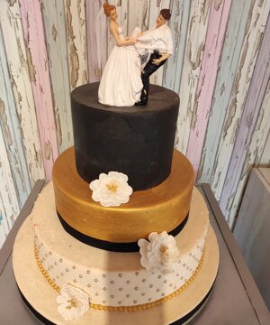 Torta bianca e nera e oro con statuetta sposi 