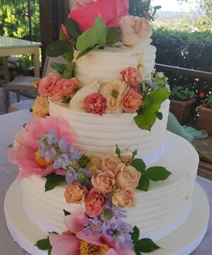 Torta bianca a piani con fiori freschi colorati