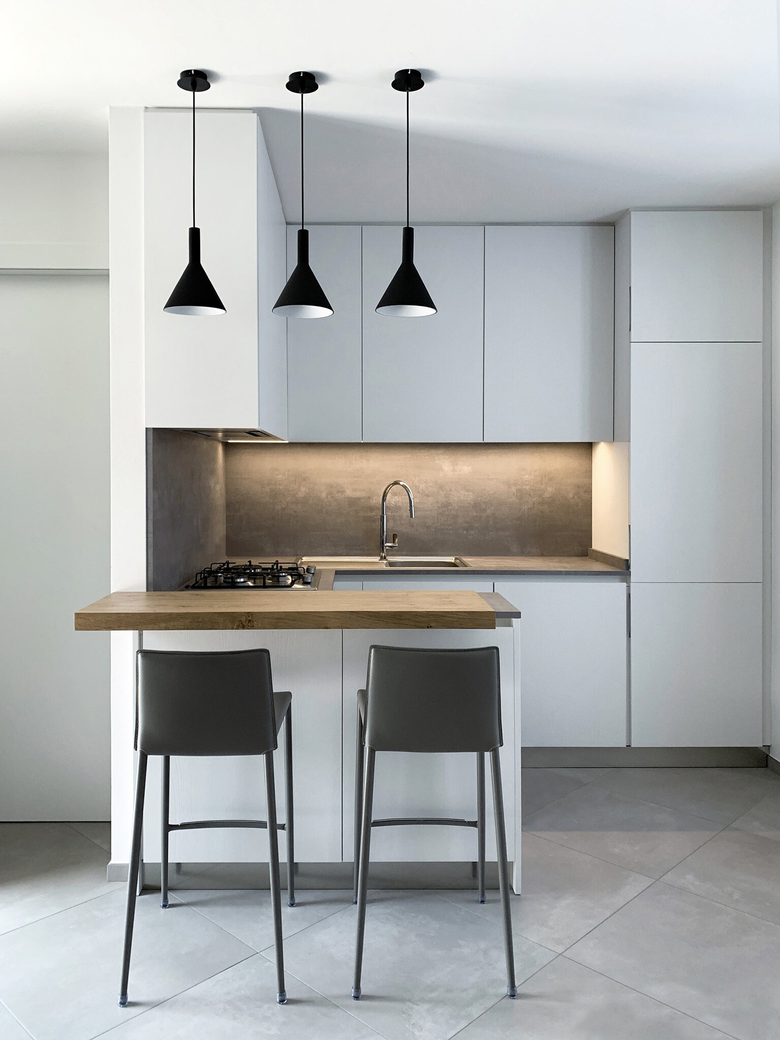 Cucina su misura ad angolo con penisola cemento e bianco: armonia tra design moderno e funzionalit&agrave;