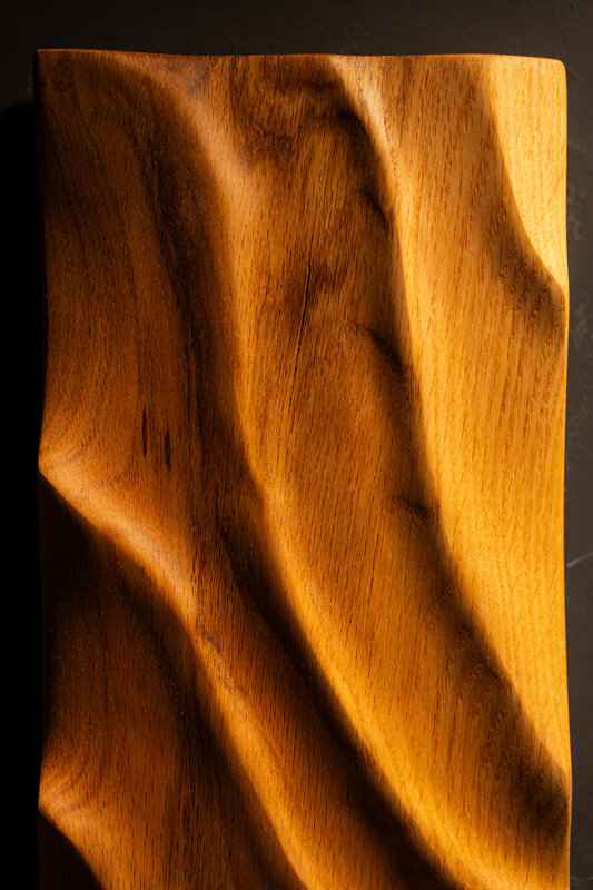 Dettaglio di opera scultorea in legno con superfici fluide e lavorazione artigianale