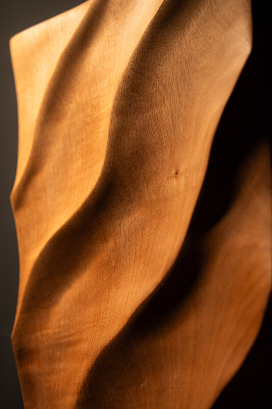 Dettaglio di opera scultorea in legno con superfici fluide e lavorazione artigianale