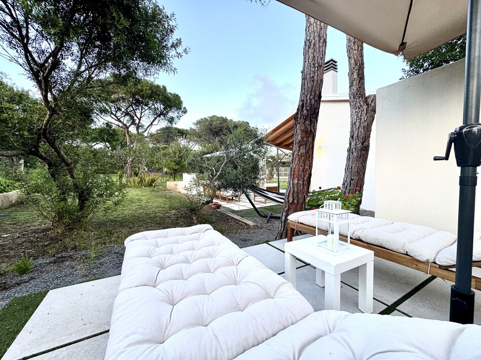 Solarium con lettini e ombrelloni affacciato sul prato.