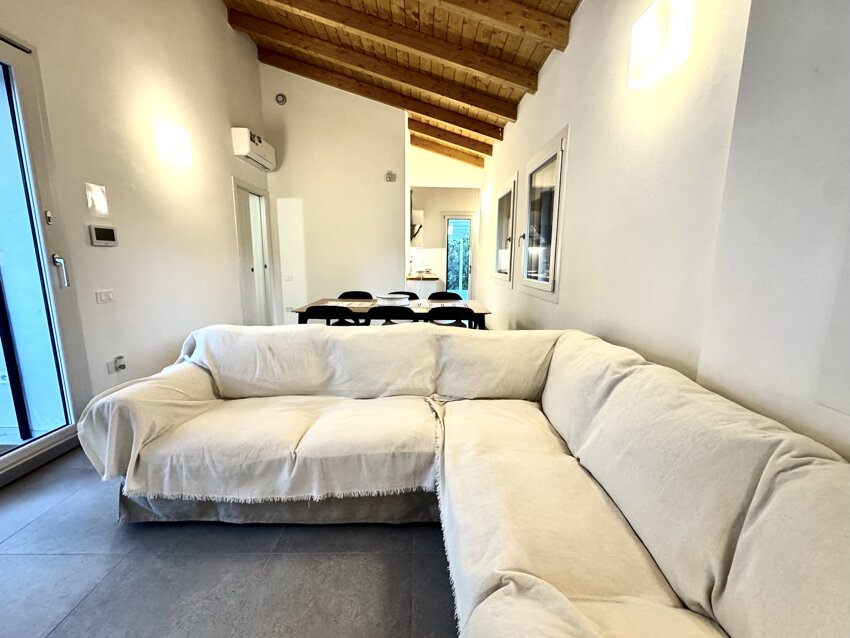 Zona living open space luminosa con divano e zona pranzo.