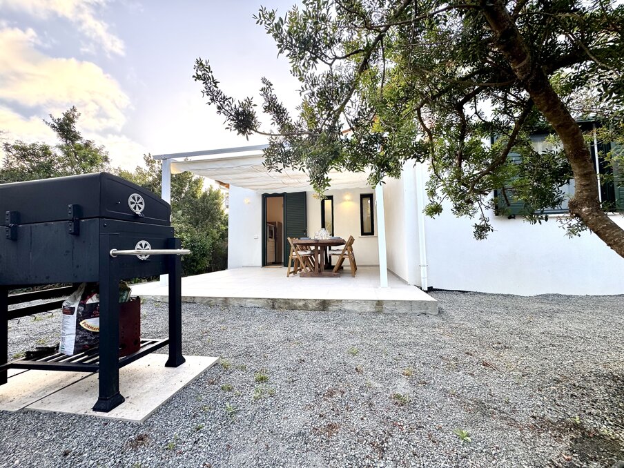 Patio con tavolo, sedie e vista sul giardino della villa.