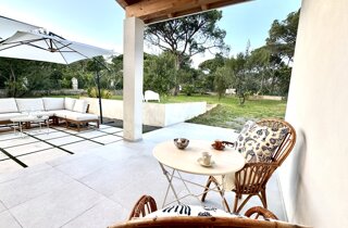 Zona relax esterna con divani e tavolino sotto il pergolato.