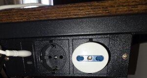 Presa elettrica sul tavolo con spina e cavo per ricarica cellulare in camera