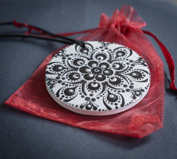 pendente circolare bianco e nero, sempre dipinto a mano, fotografato su un sacchetto di organza rosso. pendente circolare bianco e nero, sempre dipinto a mano, fotografato su un sacchetto di organza rosso.