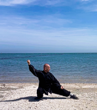 Maestro Antonio Renna che esegue una forma, in divisa sulla spiaggia Maestro Antonio Renna che esegue una forma, in divisa sulla spiaggia