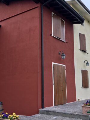 Facciata esterna ristrutturata con tinteggiatura bicolore: parete rossa intensa abbinata a parete crema chiaro