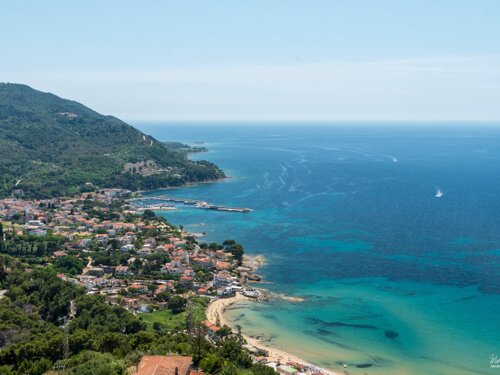 Panorama della costa del Cilento con spiagge, promontorio verde e mare cristallino dalle sfumature turchesi.