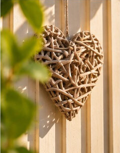 Cuore decorativo in vimini intrecciato, con foglie verdi in primo piano, tra i dettagli dell'area relax del B&B La Magnolia.
