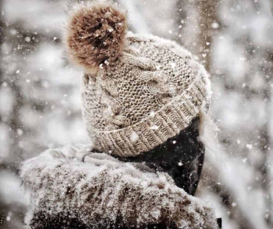 Donna di spalle in inverno, avvolta nel silenzio e nella neve, simbolo di un Natale vissuto per gli altri con grande forza interiore