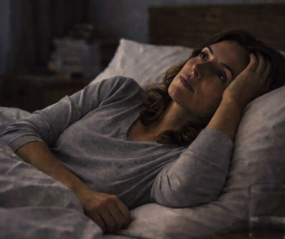 donna sveglia di notte nel letto con mente attiva e difficoltà a riaddormentarsi