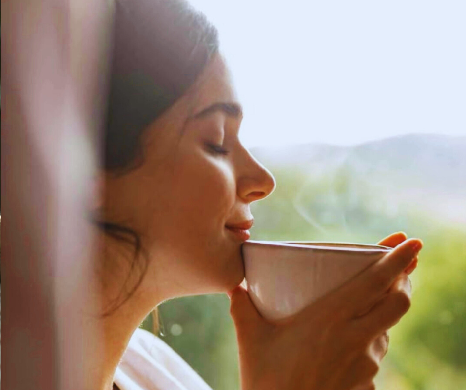 Quando l’energia torna, arriva una nuova pressione Donna con tazza calda vicino alla finestra simbolo di vivere con un ritmo lento e consapevole nello stile hygge