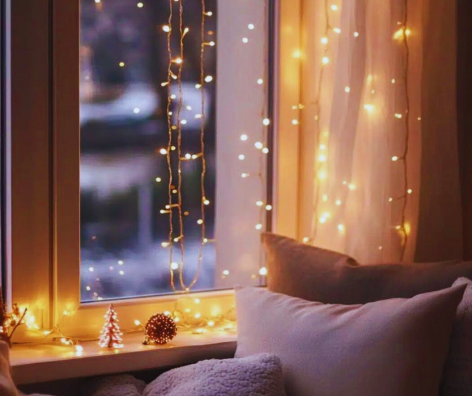 Accendere la luce dentro di sé: la saggezza hygge nel tempo del buio Luci calde accese accanto a una finestra durante l’inverno, simbolo della saggezza Hygge e del calore interiore nel tempo del buio