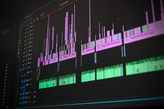 timeline di montaggio video con clip e tracce audio multicolore su monitor