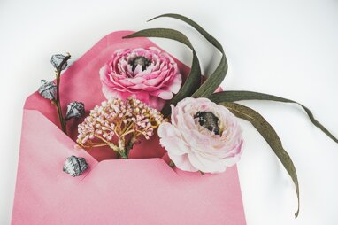 busta da lettere rosa dalla quale escono fiori e foglie su sfondo bianco